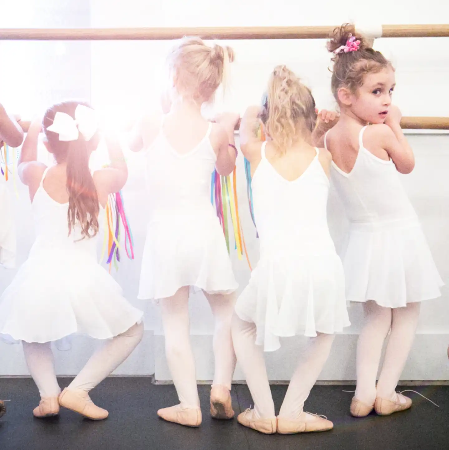 ballerina girls standing in plié at the ballet barre